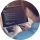 Image shows a person typing on a desktop computer, programming codes and numbers.