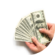 Image shows a person fanning out a multitude of $100 bills – cash.